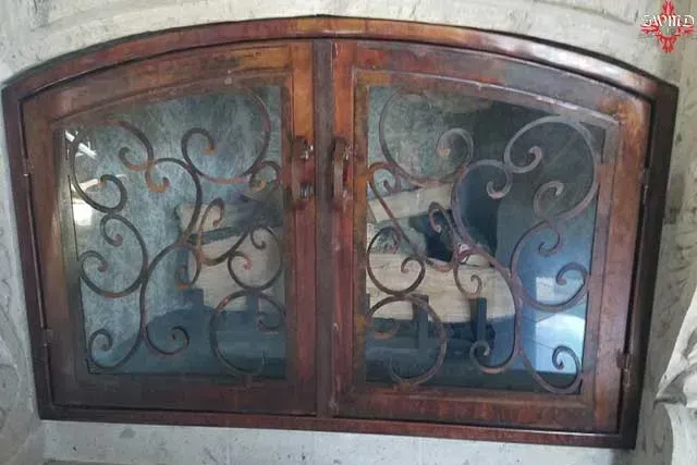 Brown arched window with decorative wrought-iron scrollwork and frosted glass panels