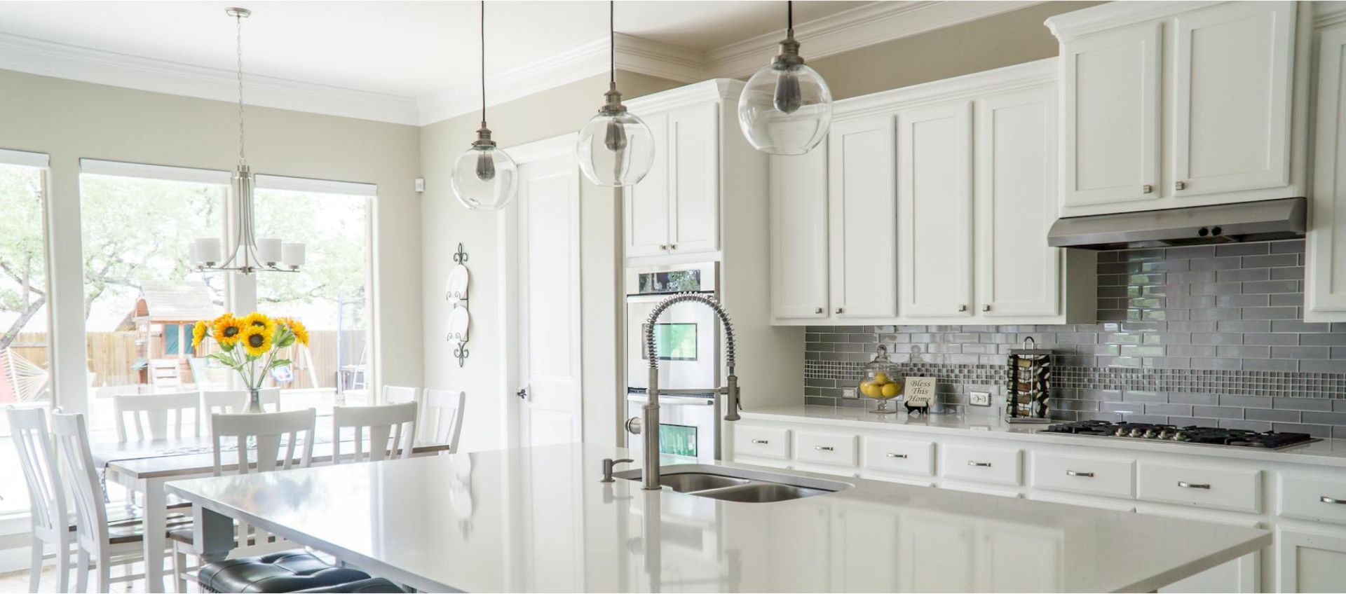 A kitchen with white cabinets , granite counter tops , stainless steel appliances and a large island.