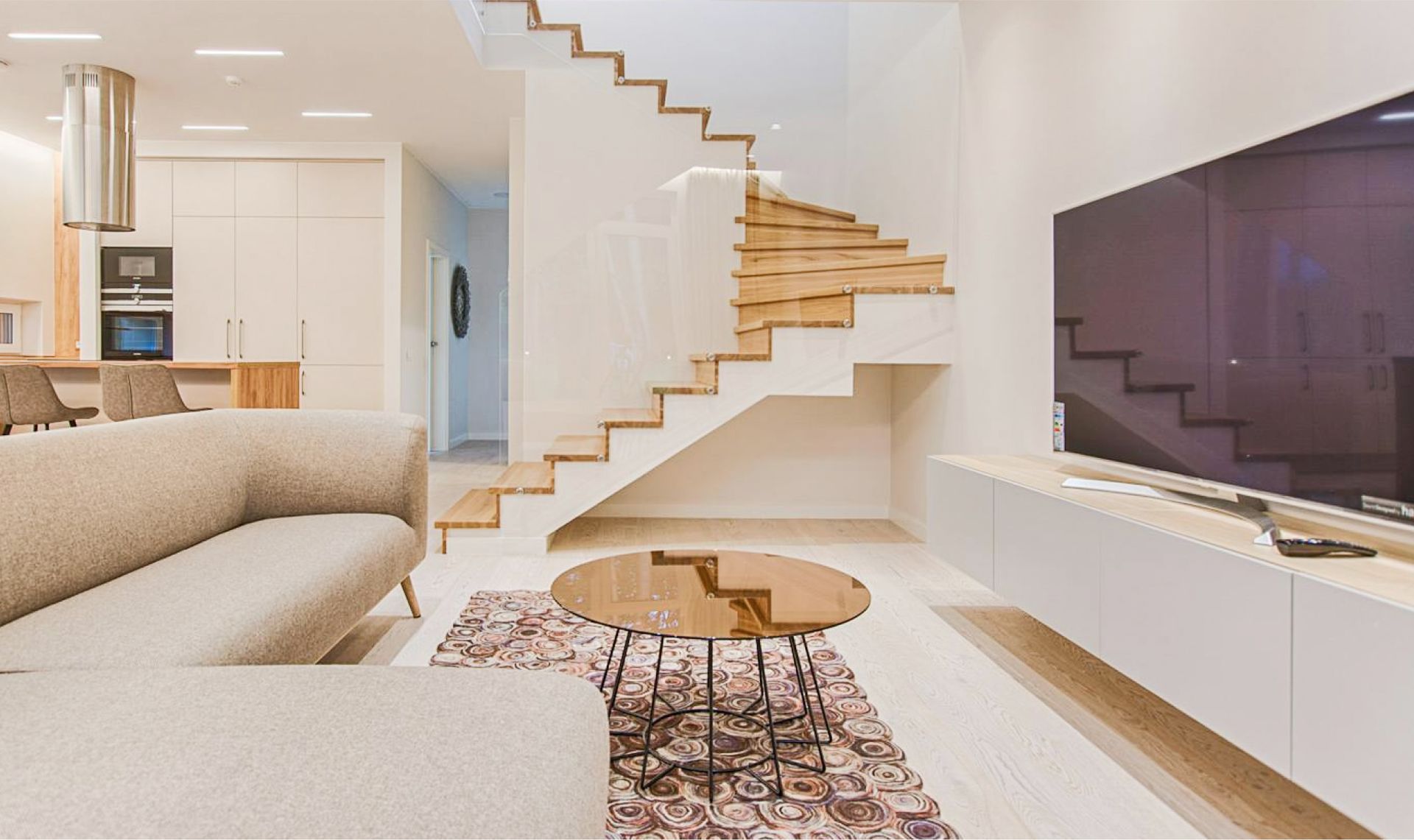 A living room with a couch , table , television and stairs.