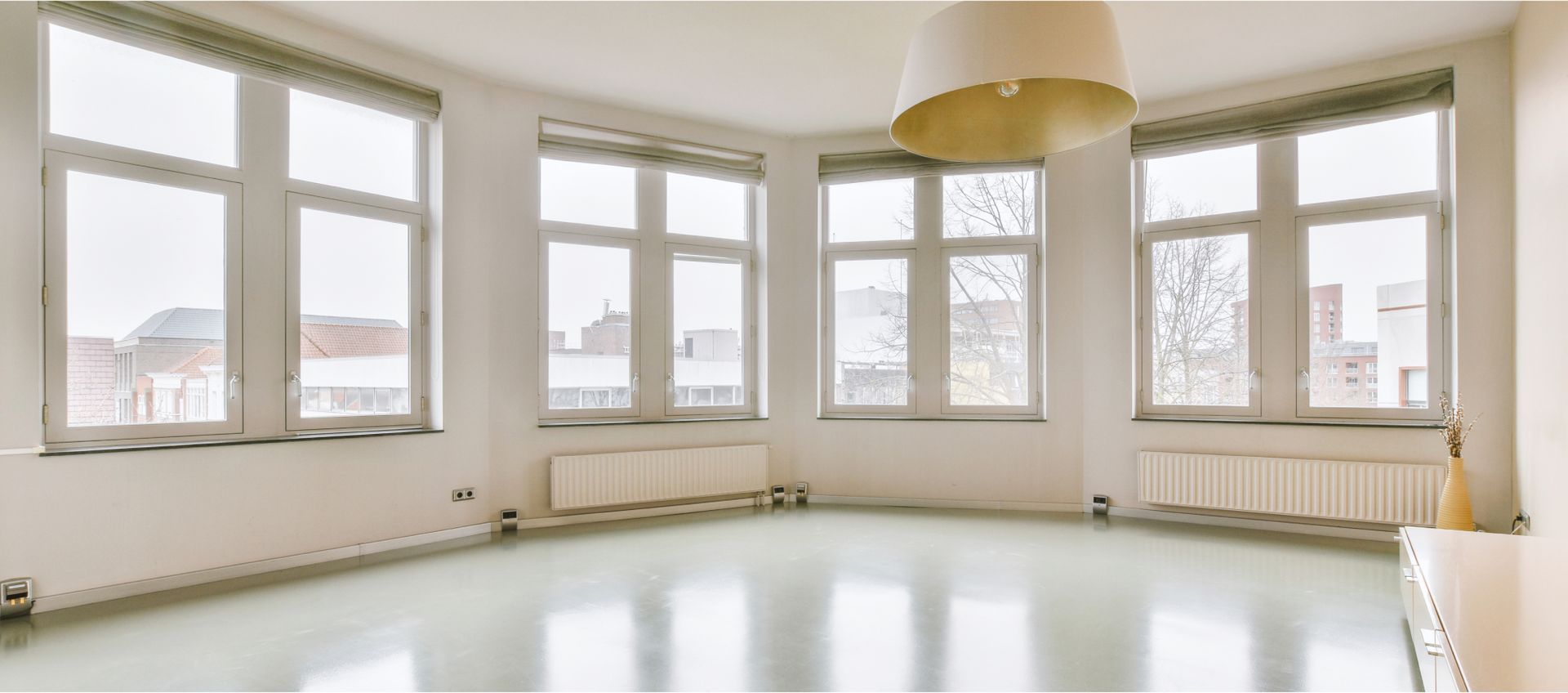 An empty room with a lot of windows and a ceiling light.