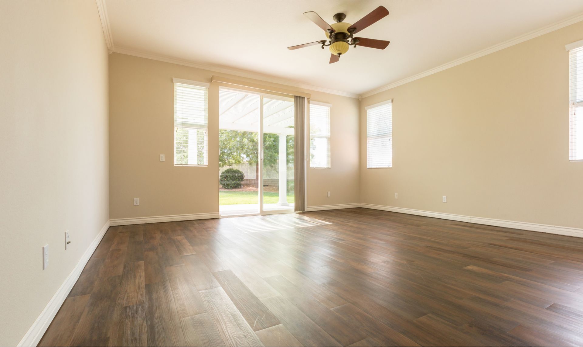 An empty living room with hardwood floors and a ceiling fan.