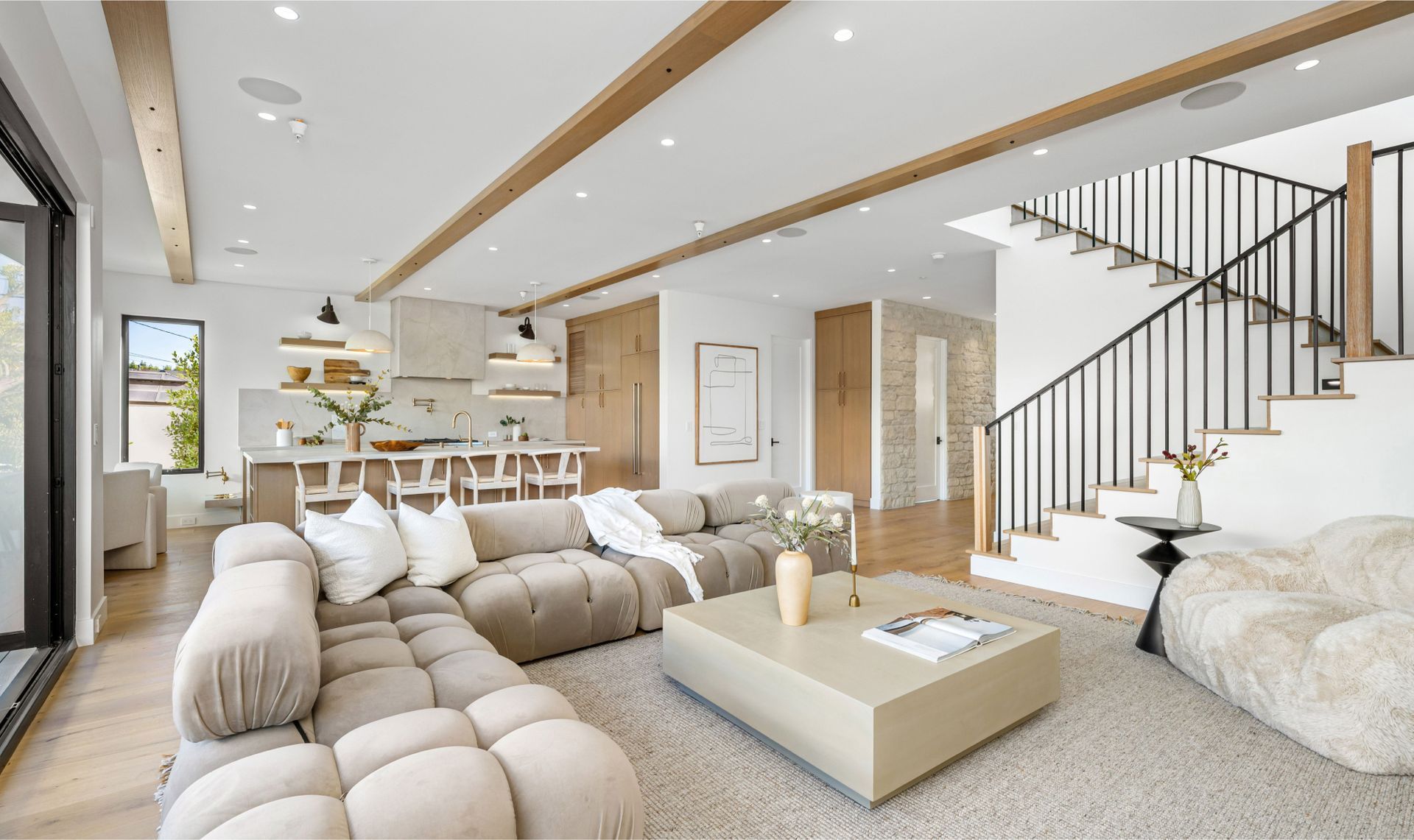 A living room with a couch , coffee table , chairs and stairs.