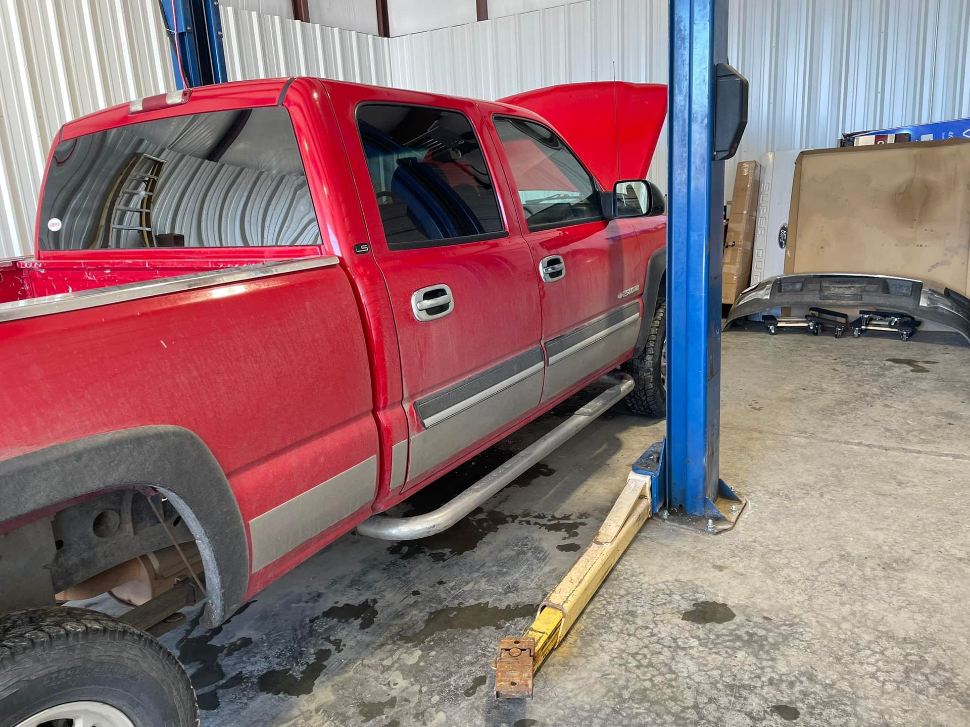 Red pickup truck being worked on inside a garage; hood open.
