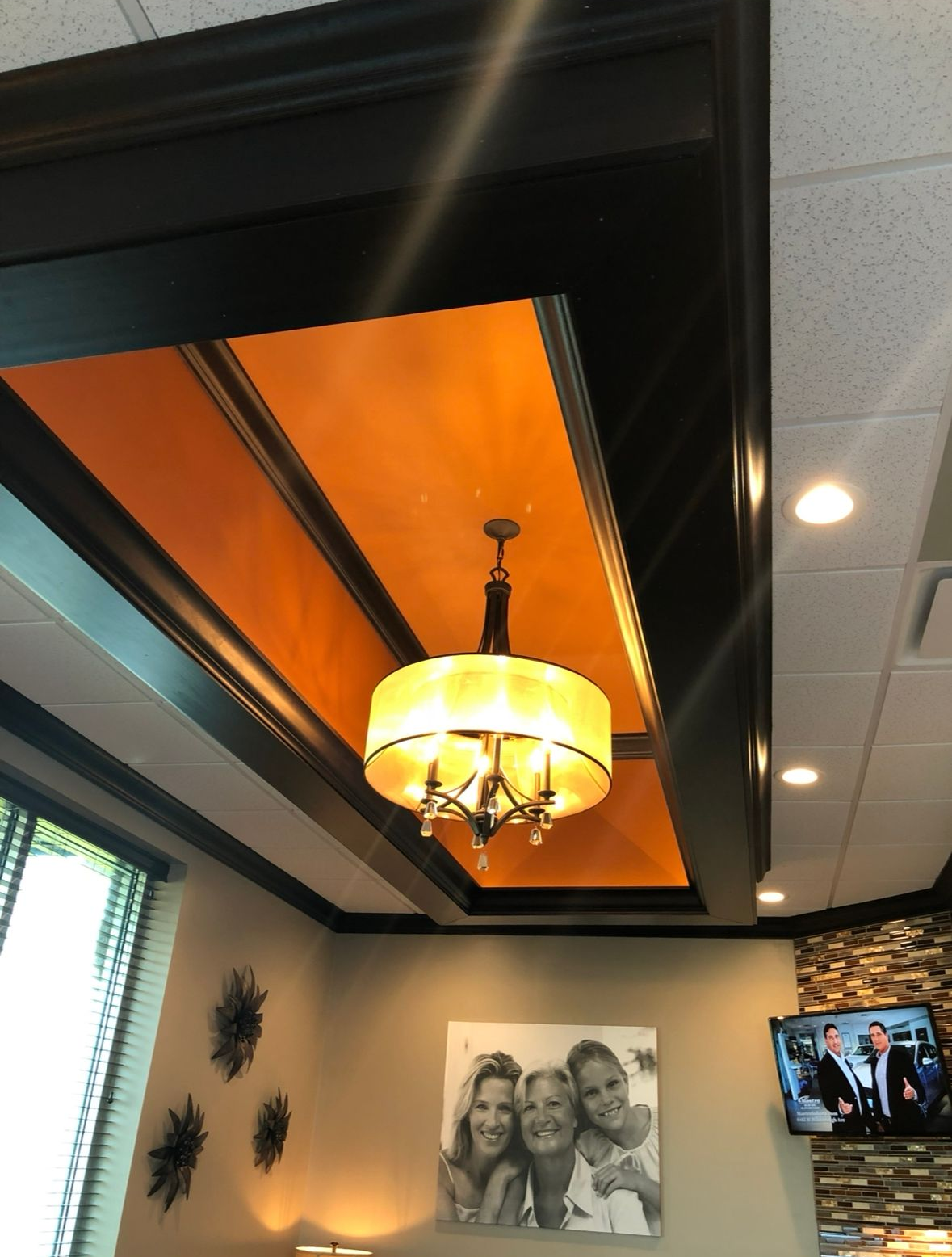 Orange ceiling with black trim, chandelier, framed photo, and stone wall.