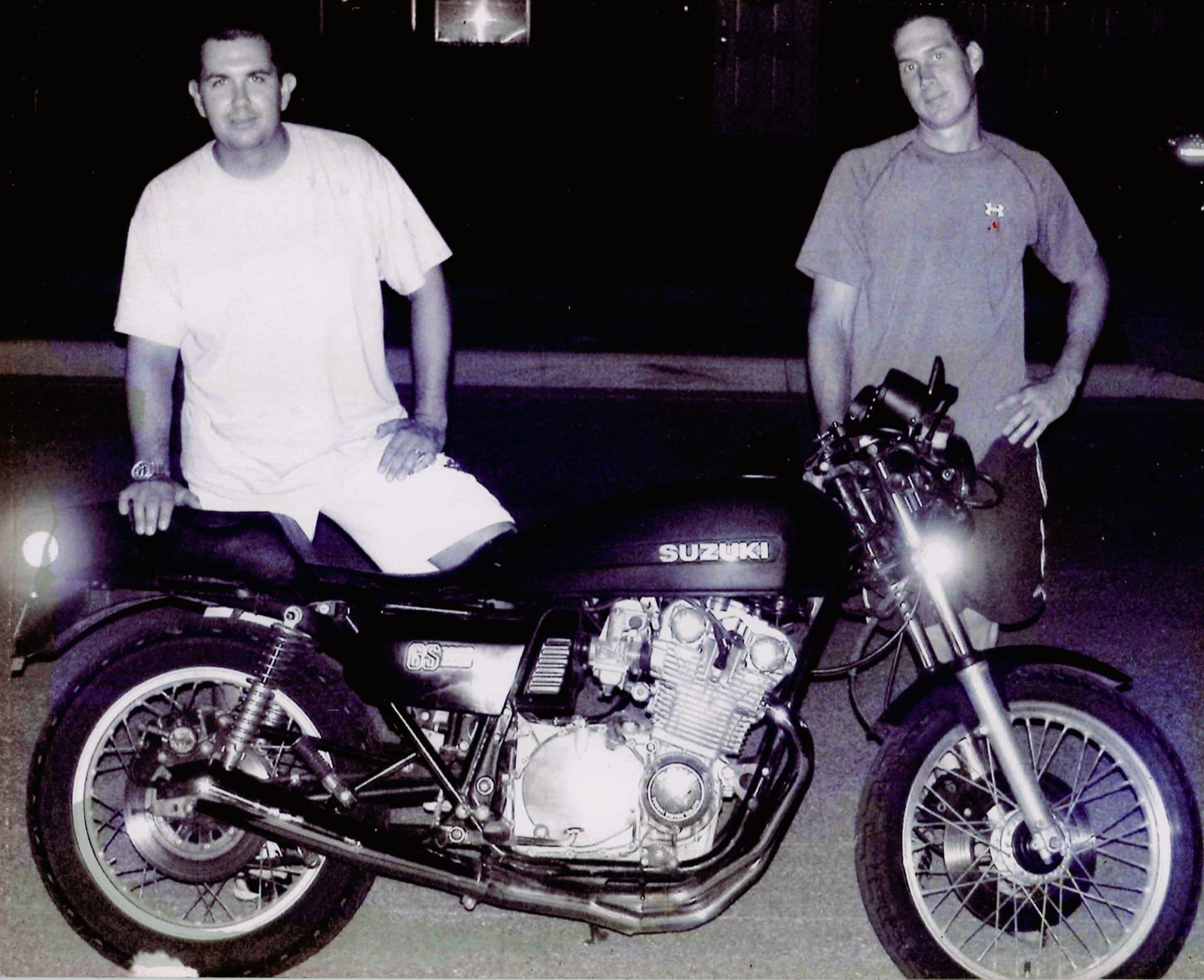 Two men standing next to a suzuki motorcycle