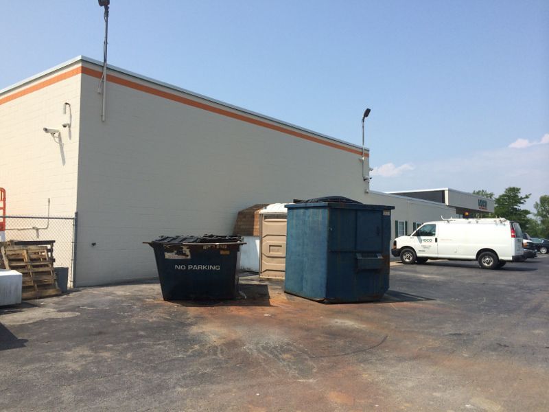 Fresh Coat of Grey Paint on Commercial Building Behind Dumpsters
