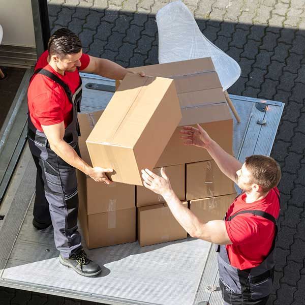 Male Movers Unloading The Cardboard Boxes Form Truck 
