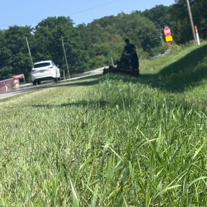 A man is mowing his lawn with a red lawn mower.