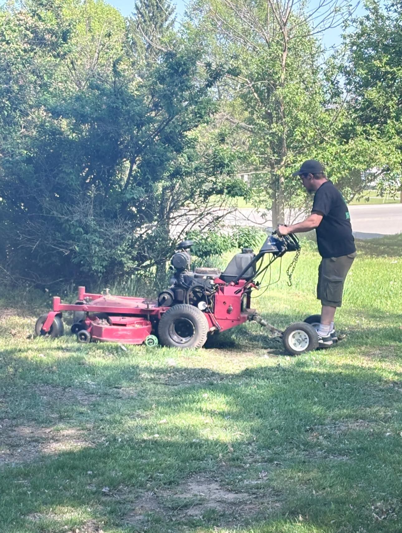 A man is mowing his lawn with a red lawn mower.