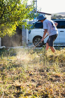 A man is mowing the grass in front of a white van.