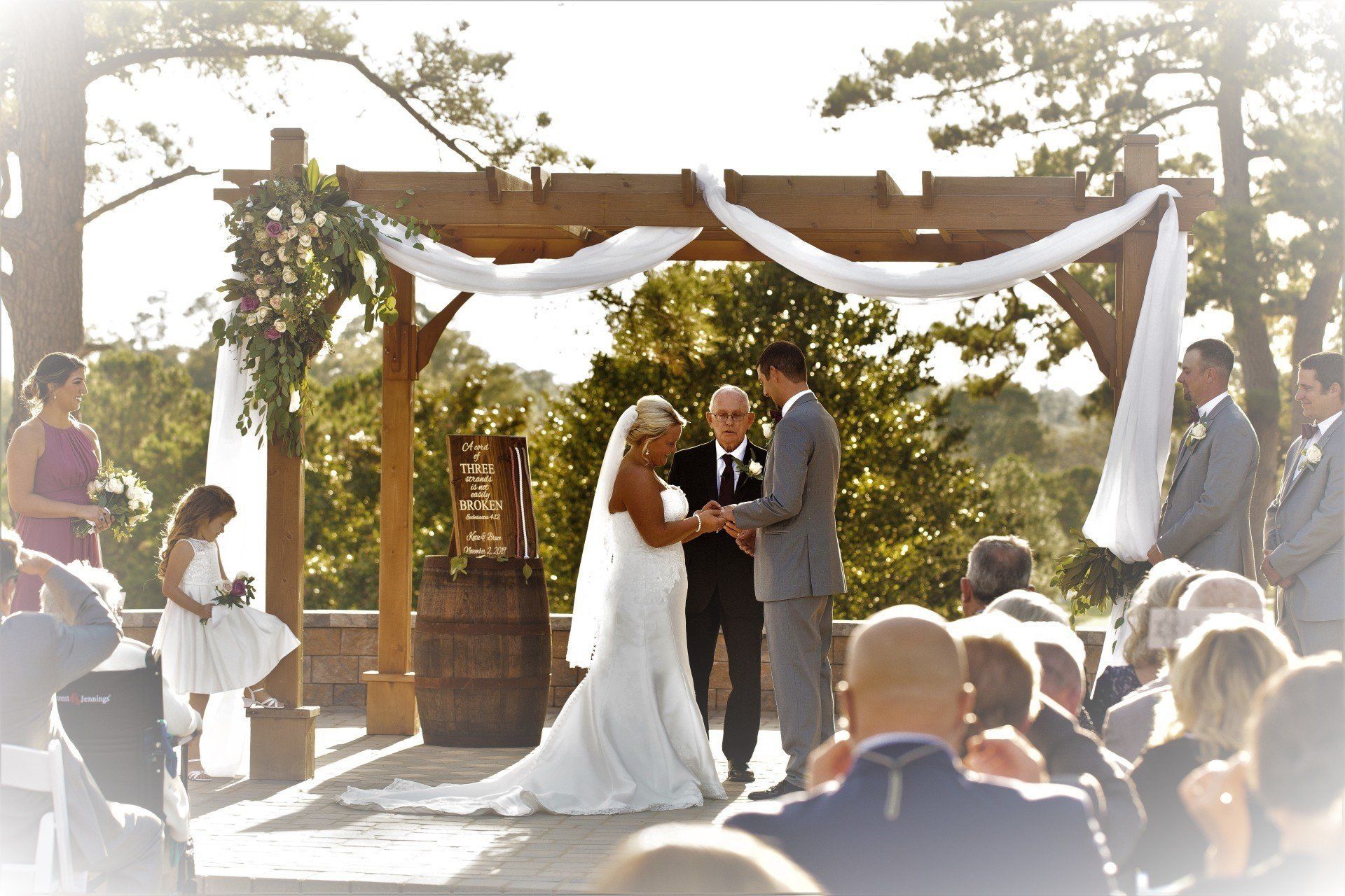 A bride and groom are getting married under a pergola A bride and groom are getting married under a pergola
