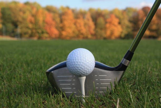 A golf ball is on a tee next to a golf club.
