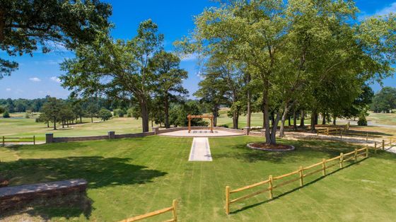 An aerial view of a large grassy field with trees and a wooden fence.