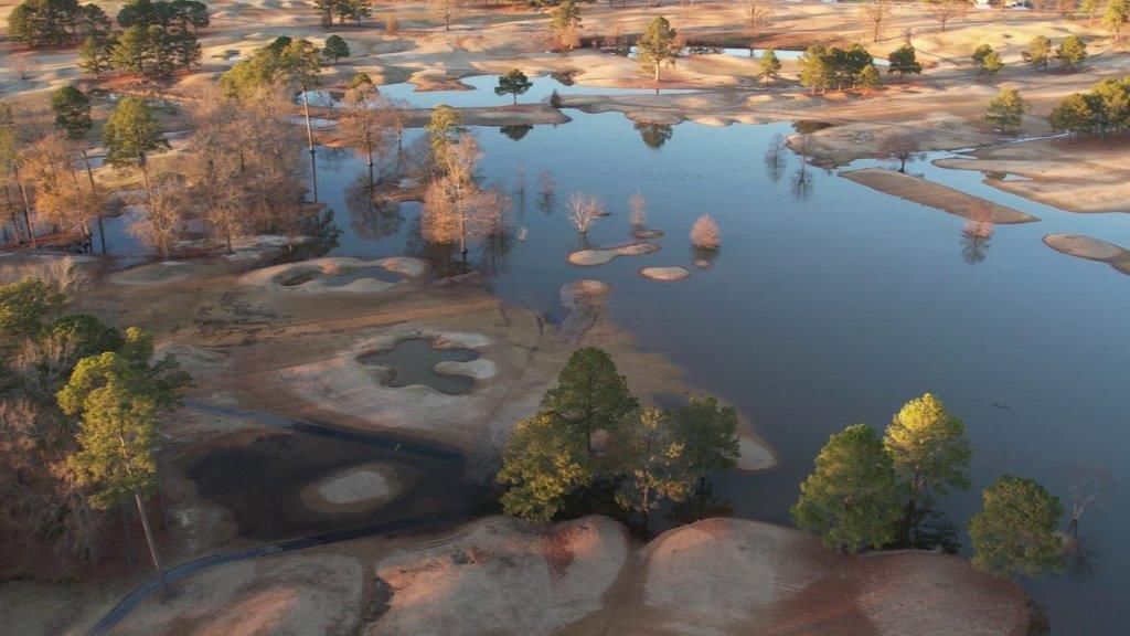 An aerial view of a lake surrounded by trees and dirt.