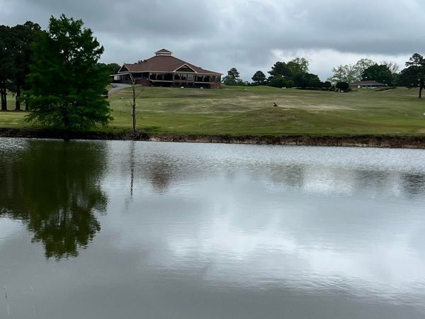 A lake with a house in the background and trees in the foreground