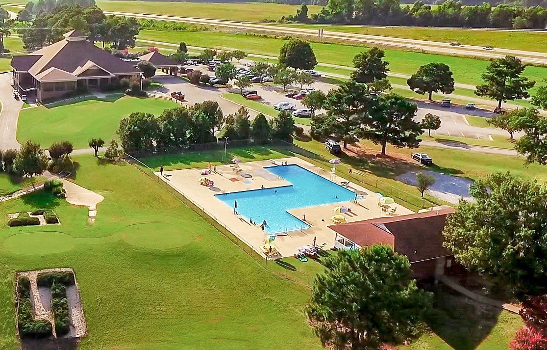 An aerial view of a swimming pool surrounded by trees and grass.