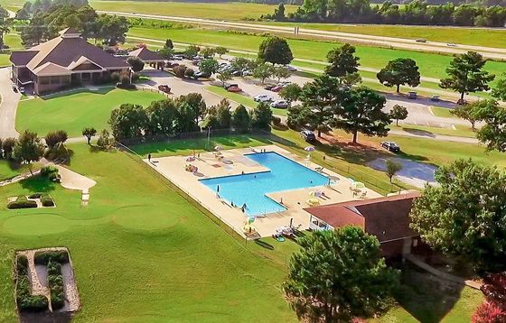 An aerial view of a swimming pool surrounded by trees and grass.