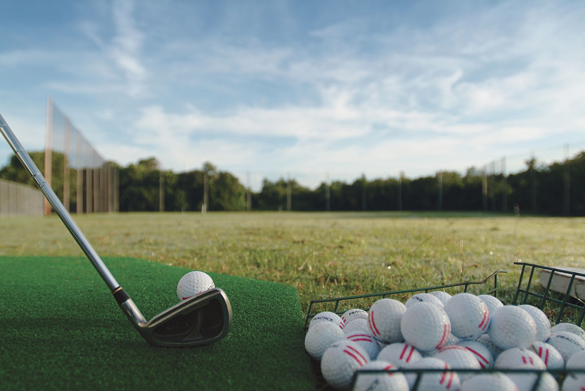 A golf club is sitting on top of a pile of golf balls.