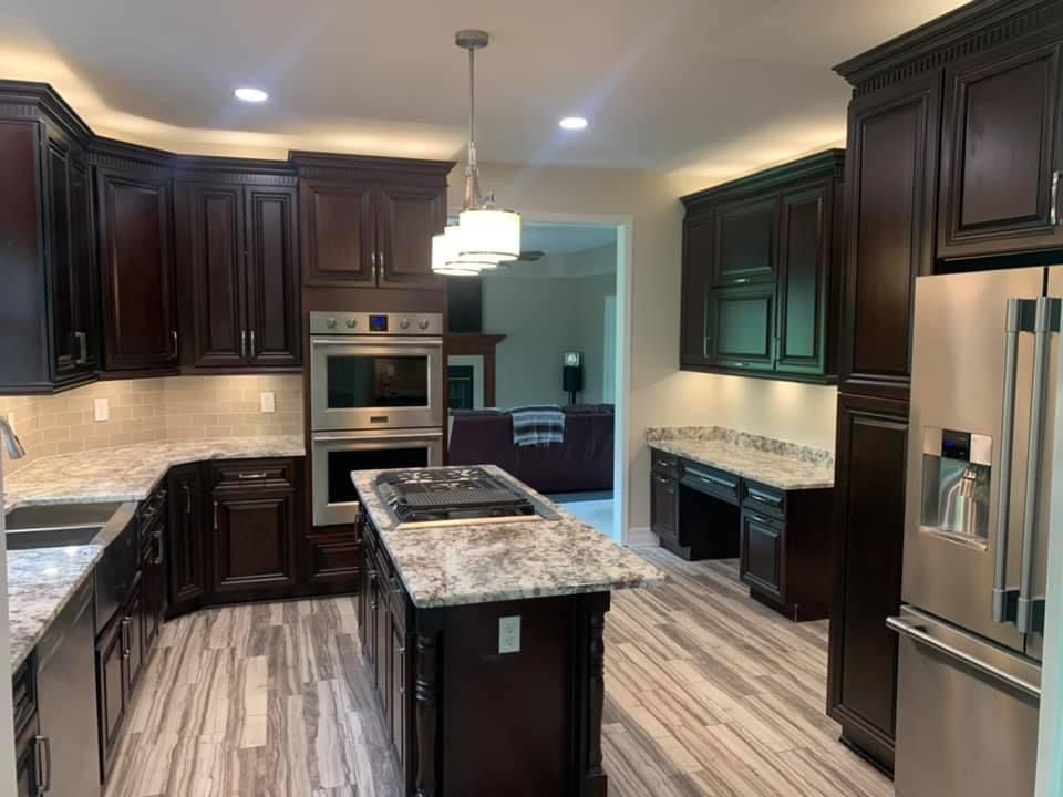 Dark wood kitchen with granite countertops, stainless steel appliances, and light-colored wood floors.