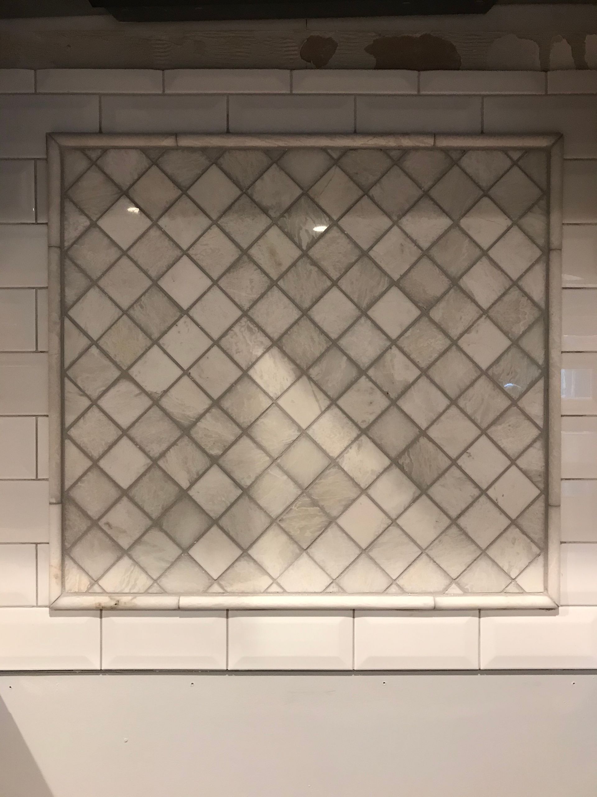 Diamond pattern tile inset within white subway tile.