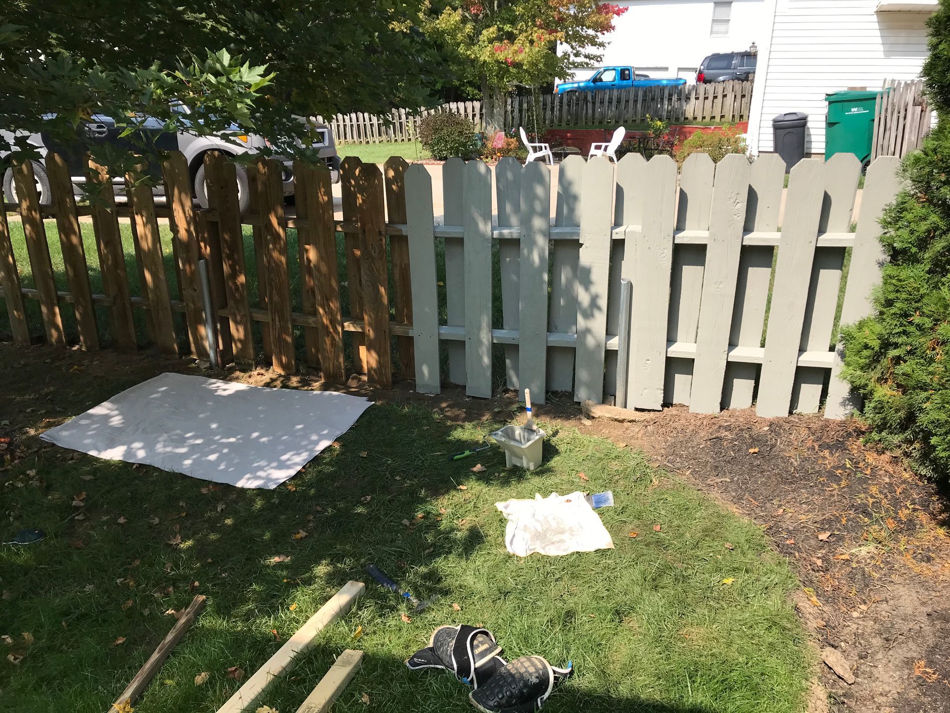 A wooden fence partially painted gray and brown in a yard with grass.