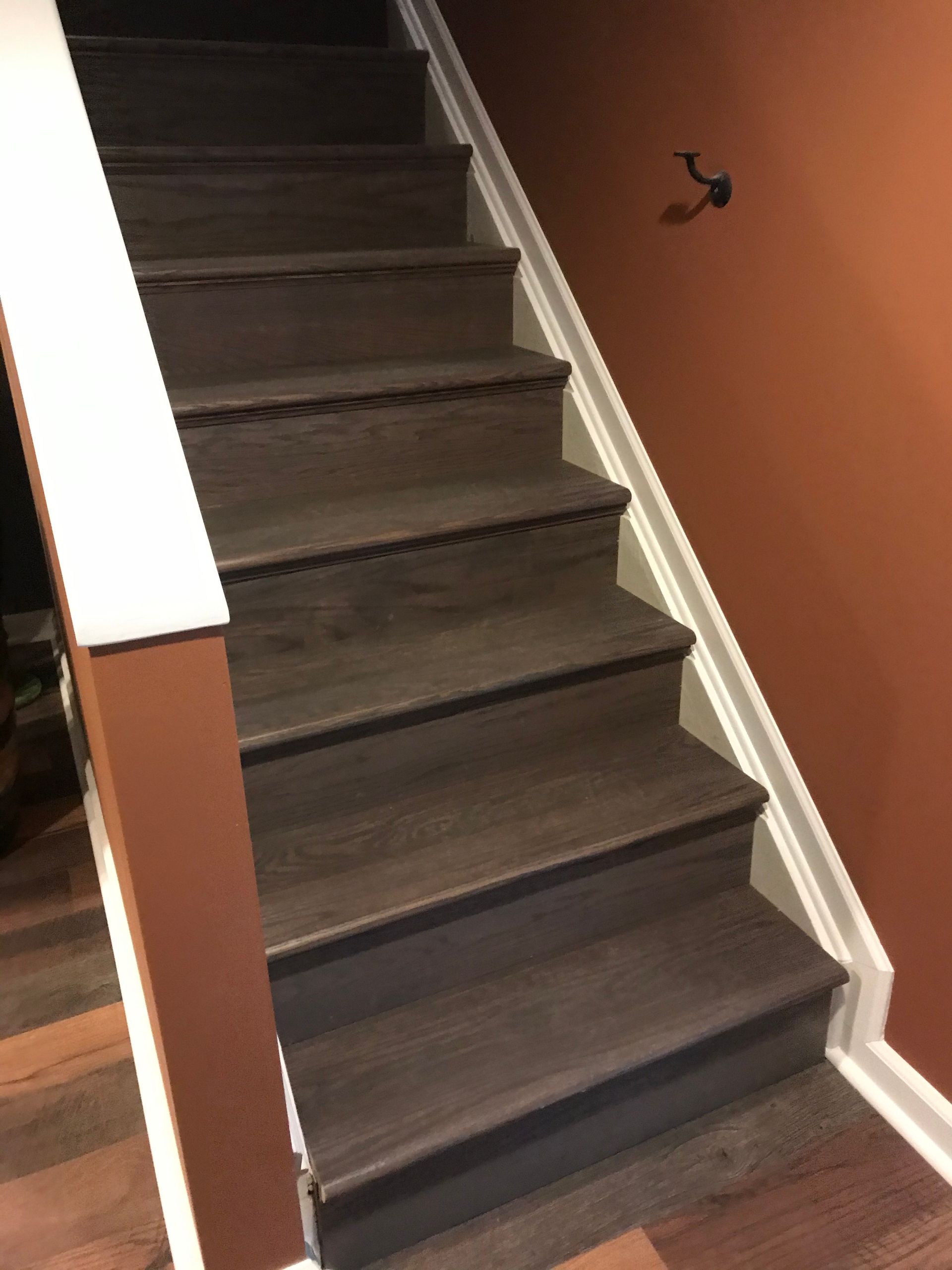 Dark wooden staircase with white trim on one side, brown paint on the other.