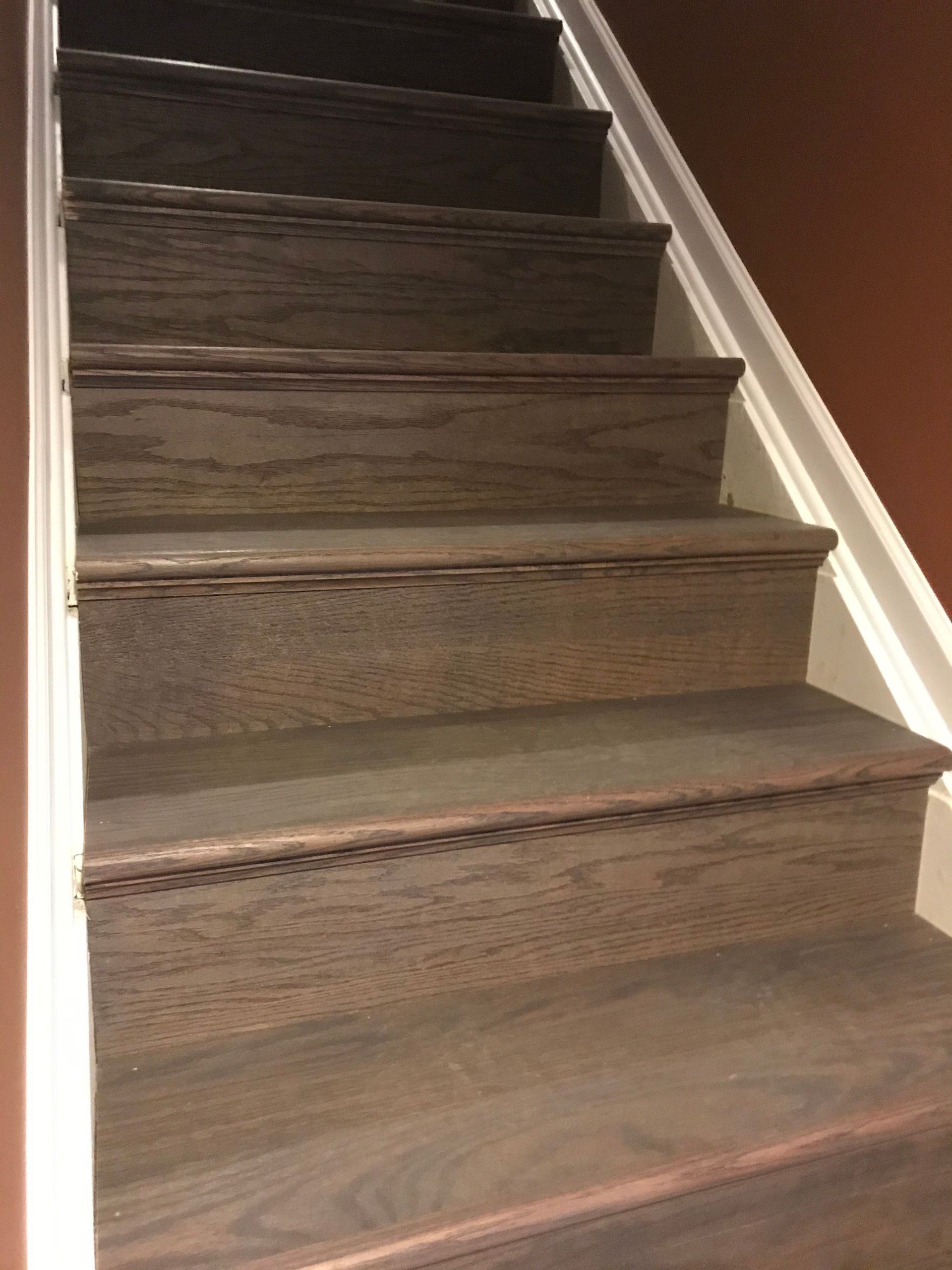 Wooden staircase with dark treads, white trim, and a brown wall.