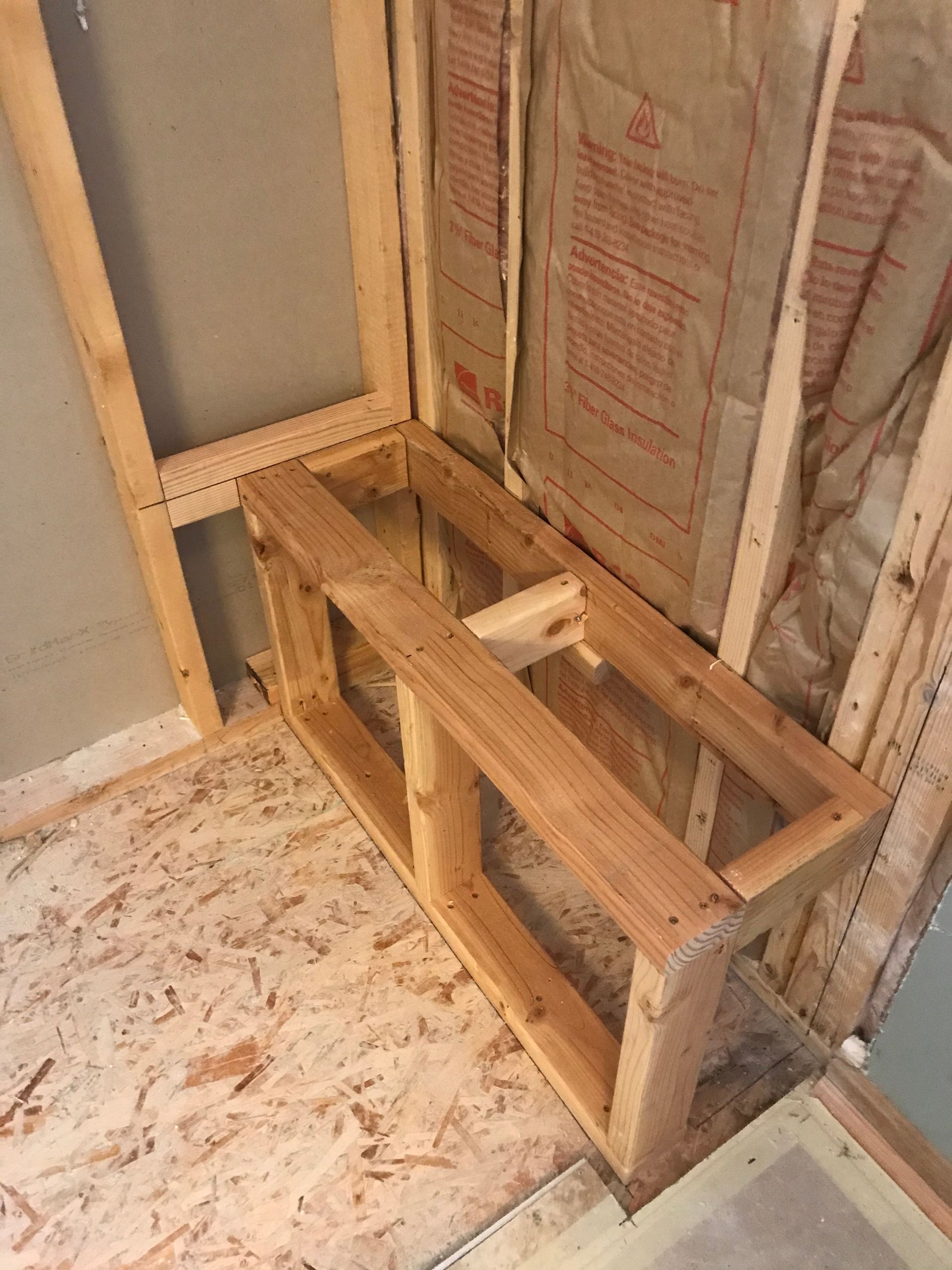 Wooden framework for a built-in bench in a partially constructed room.