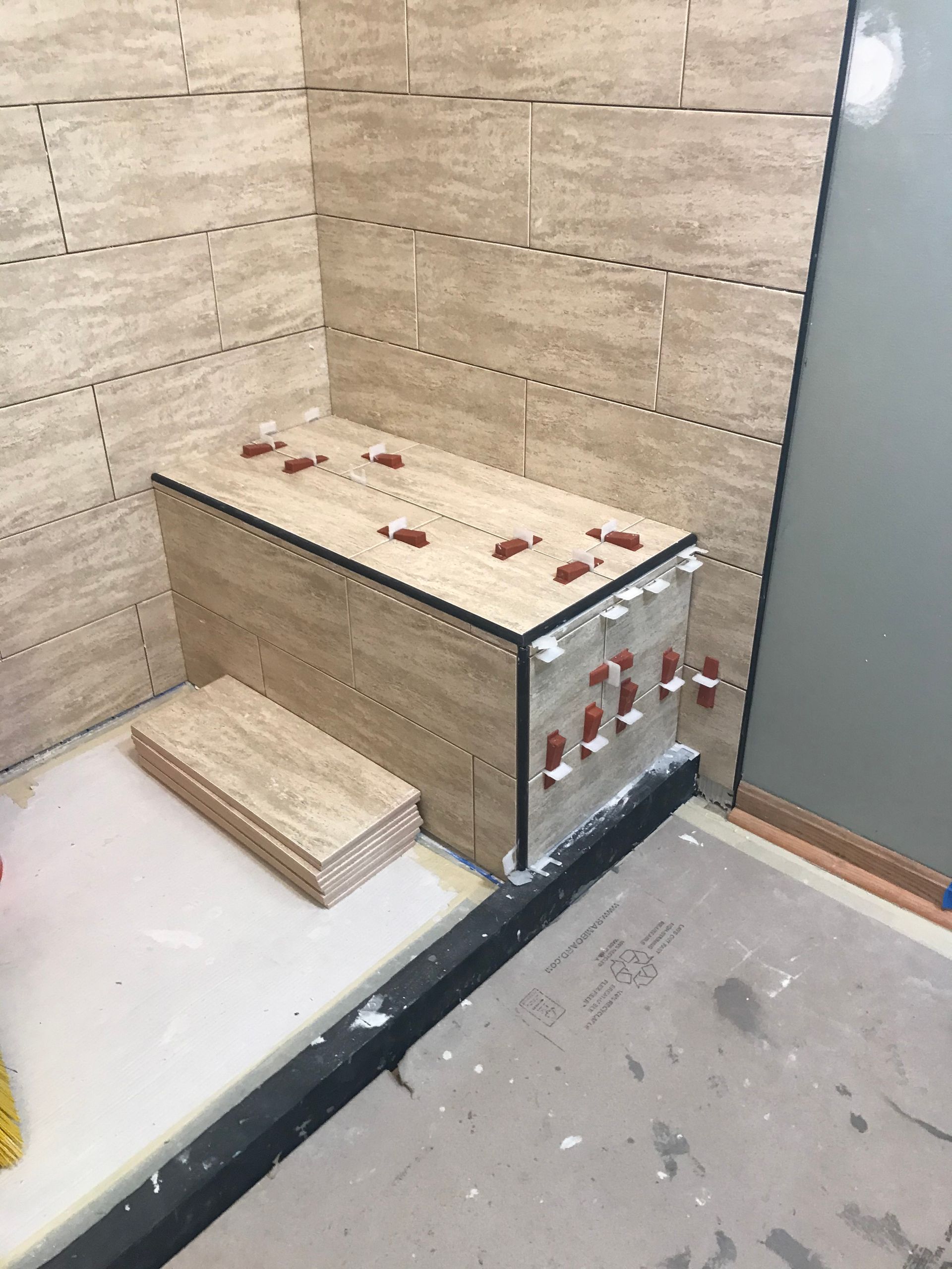 Shower stall under construction; tiled walls and a bench with tile spacers.