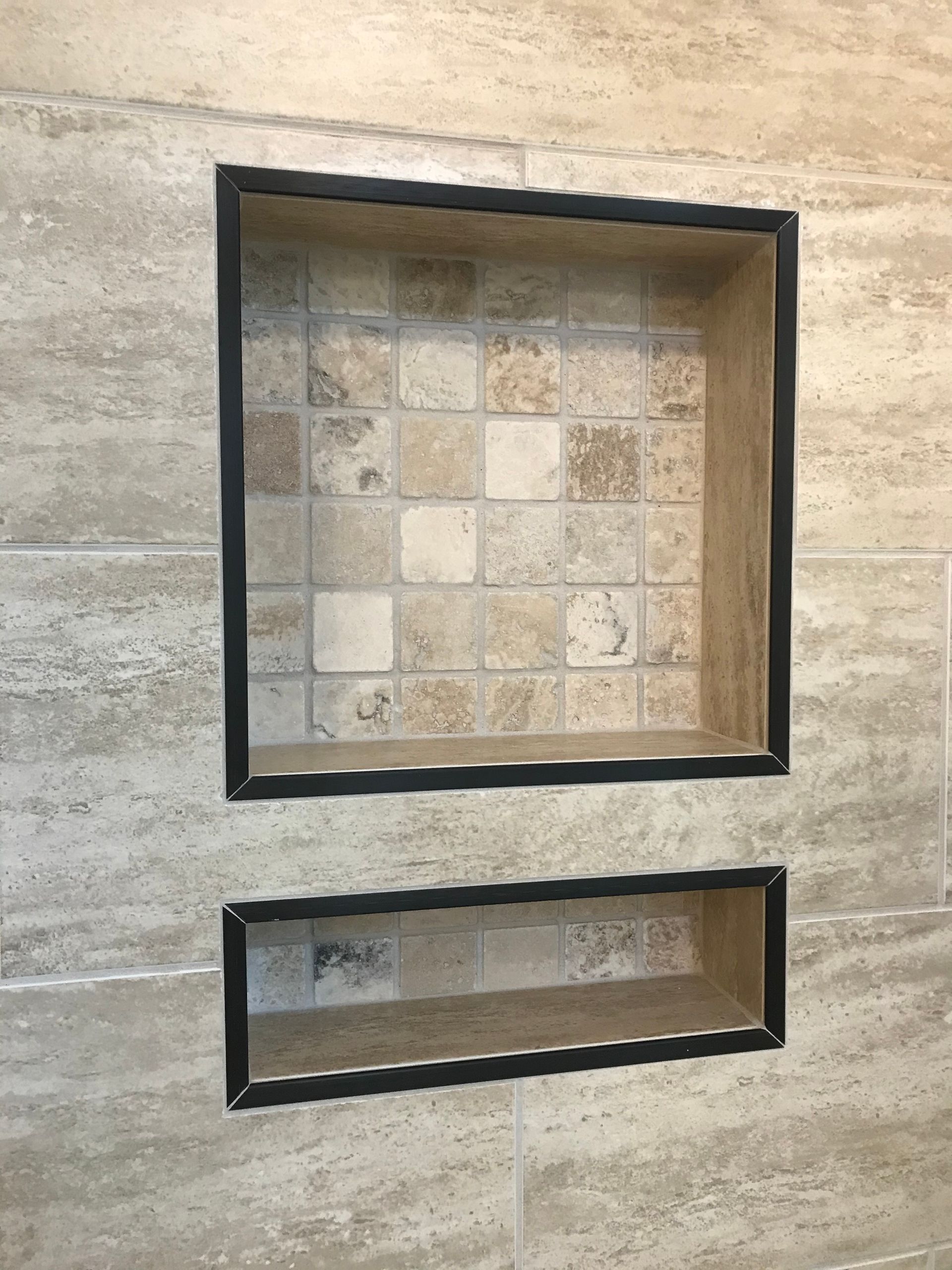 Two tile niches in a shower wall. The top is square, the bottom is rectangular. Both have black borders.