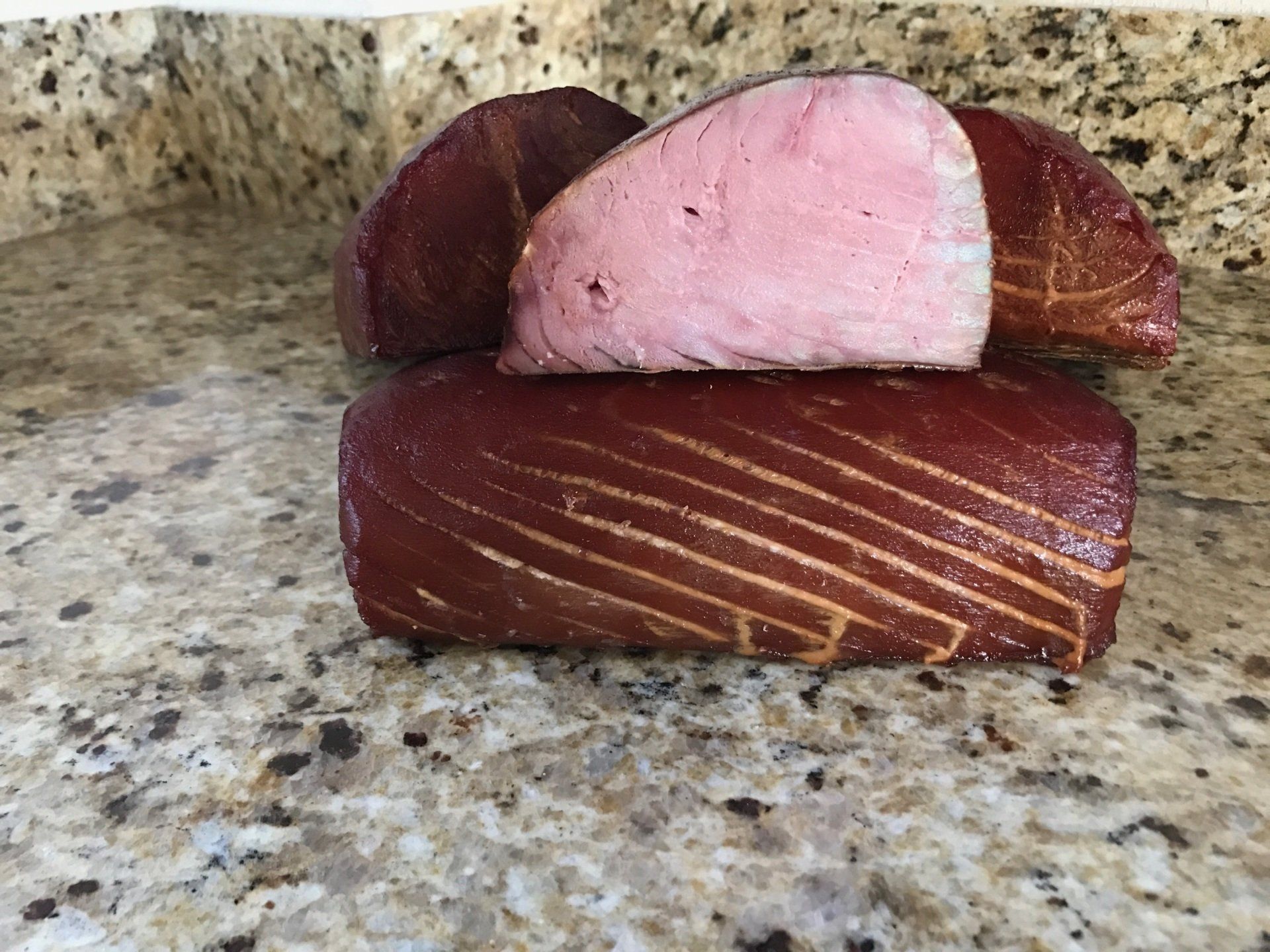 Chunks of smoked tuna, brown exterior, pink interior, on a granite countertop.