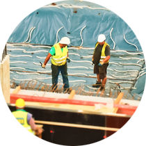 Two construction workers wearing hard hats are working on a building
