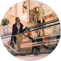 A woman is walking down an escalator in a shopping mall.