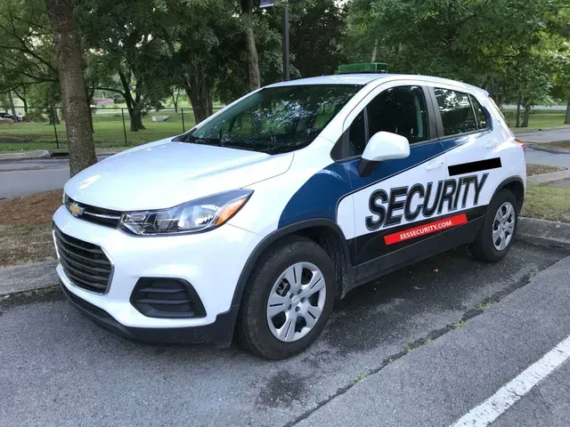 A white and blue security car is parked in a parking lot.