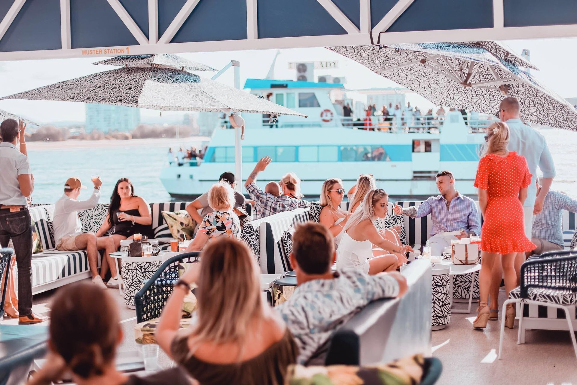 A Group of People Are Sitting at Tables in Front of A Boat — Club Nautical in Gold Coast, QLD
