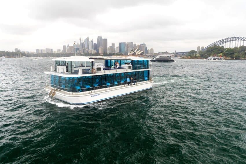 A large boat is floating on top of a body of water in front of the opera house.