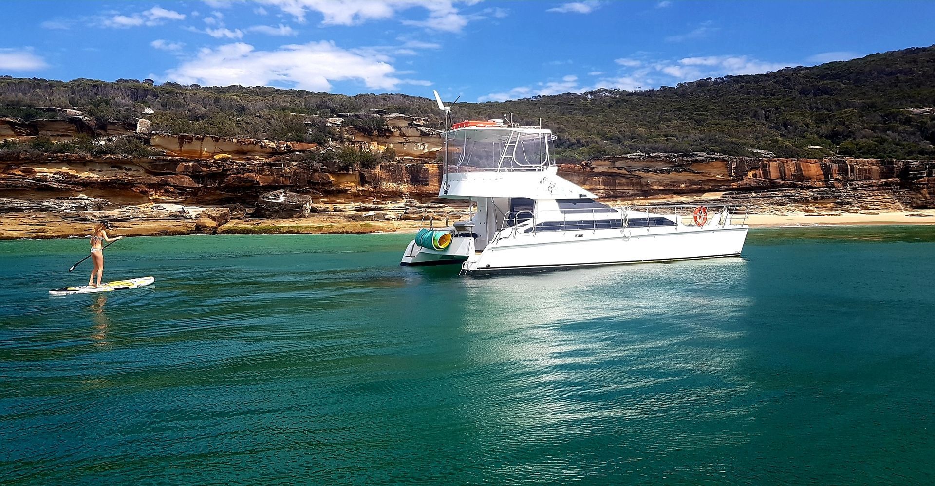 A group of people are on a boat in the water with a city skyline in the background.