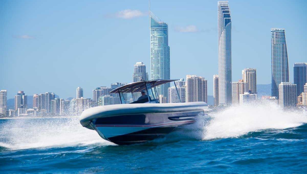 A boat is floating on a body of water in front of a row of houses.