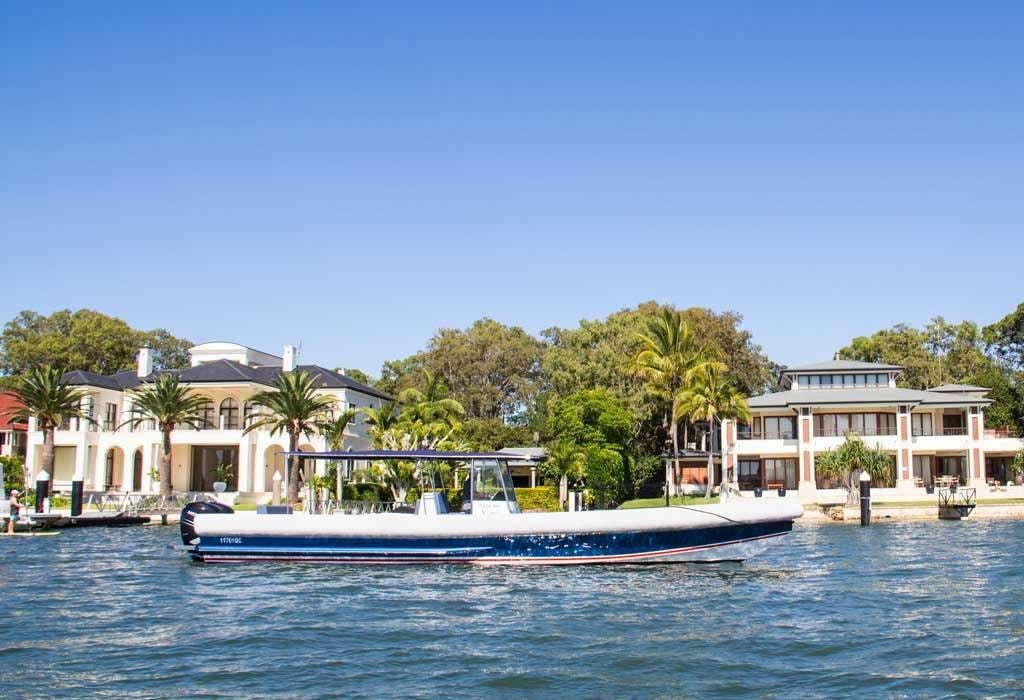 A boat is floating on a body of water in front of a row of houses.