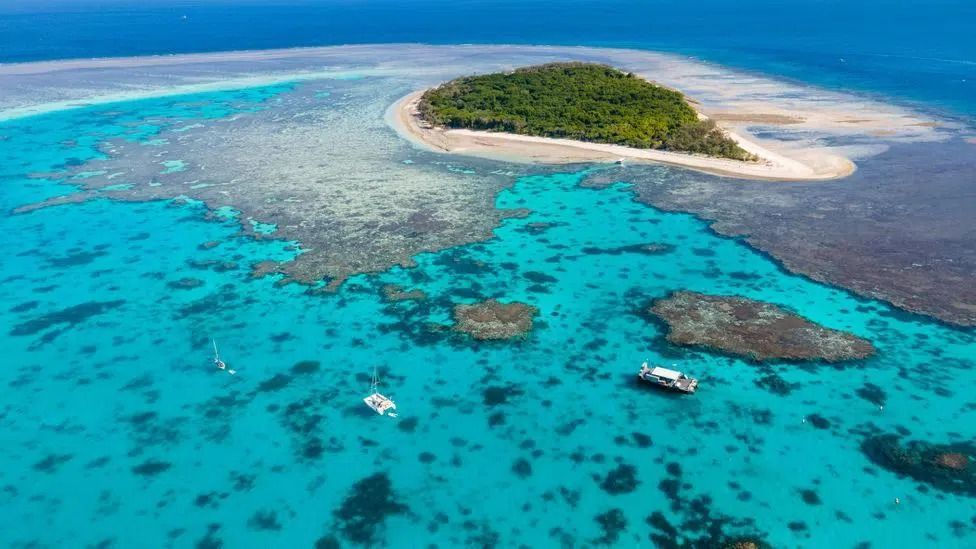 an Aerial View of a Small Island in the Middle of the Ocean Surrounded by Coral Reef — Club Nautical in Gold Coast, QLD