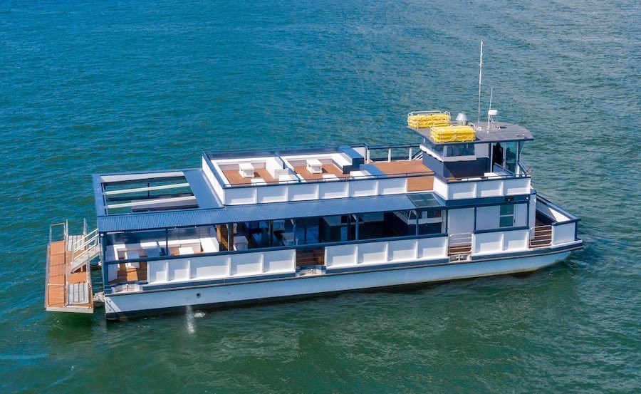 A boat is floating on top of a body of water in front of a bridge.