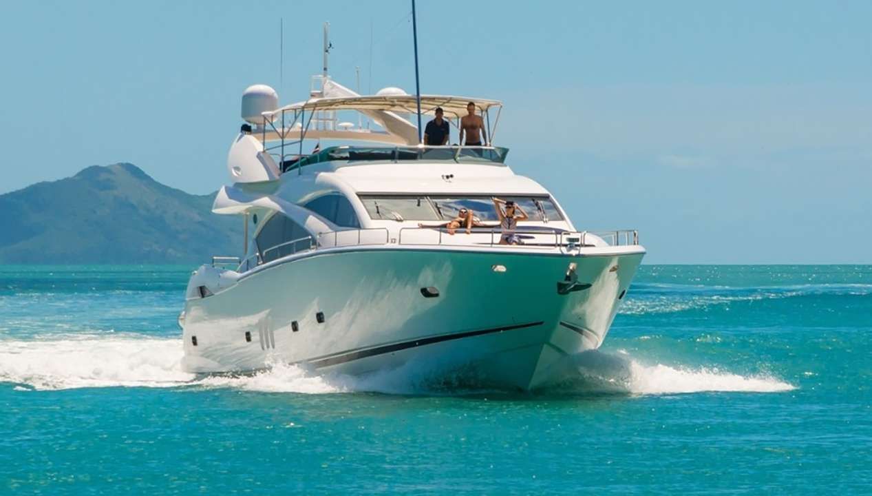 A white yacht with a water slide attached to the side is floating on top of a body of water.