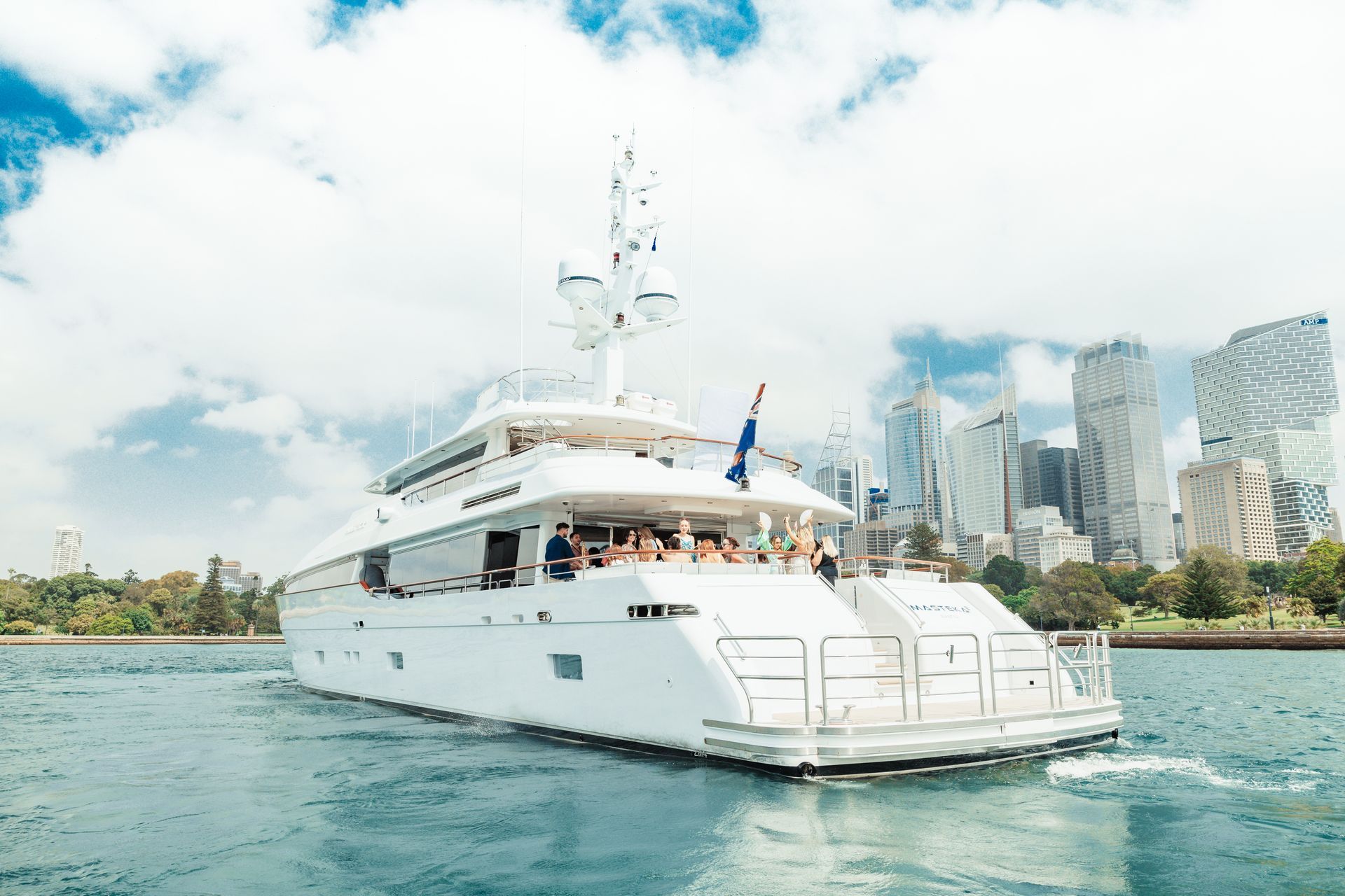 White yacht sailing on blue water, under a cloudy sky.