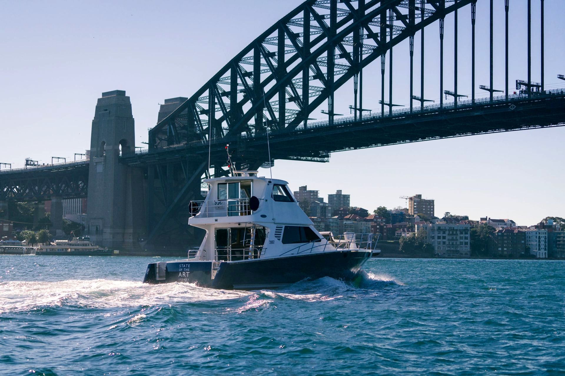 A Boat Is Going Under the Sydney Harbour Bridge in The Water — Club Nautical in Gold Coast, QLD
