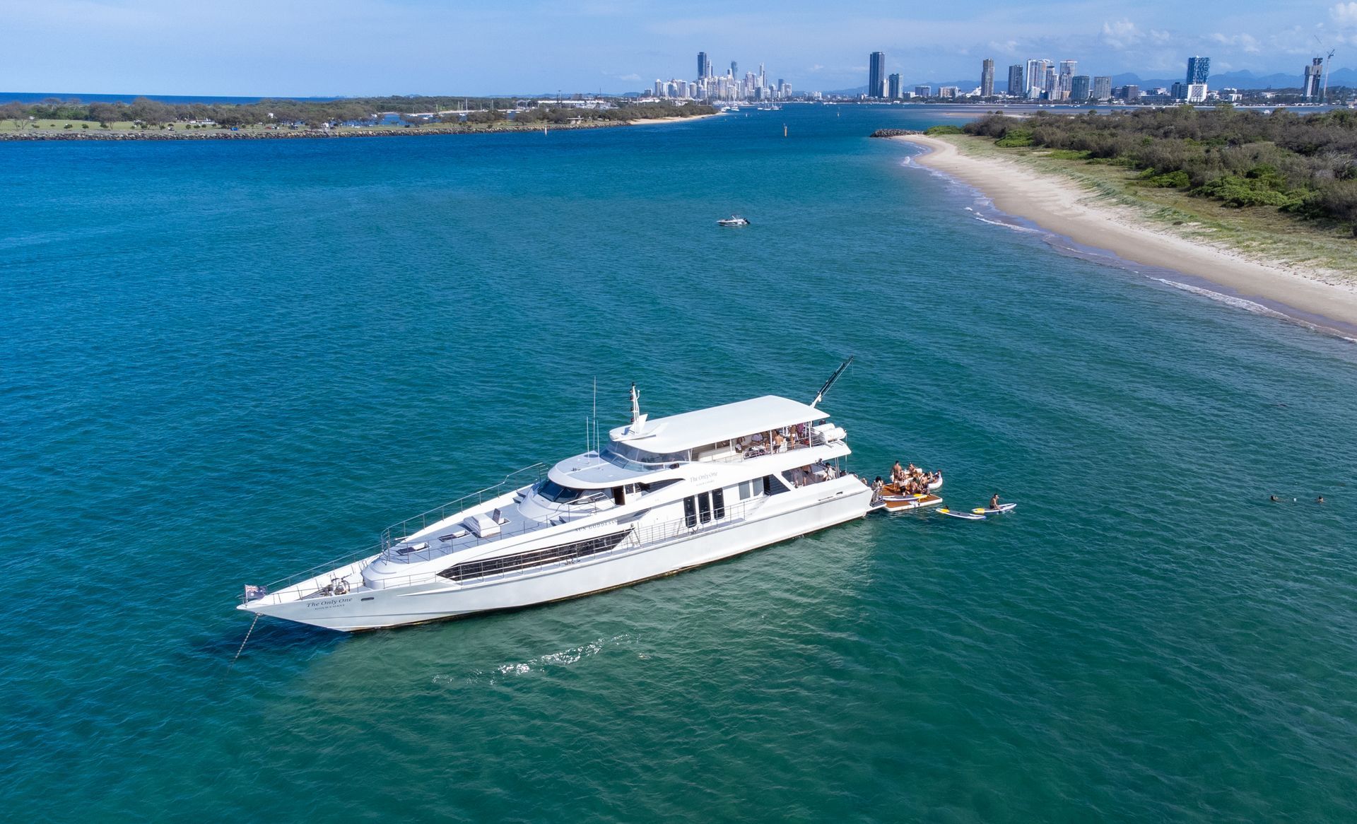 A large white yacht is floating on top of a body of water near a beach.