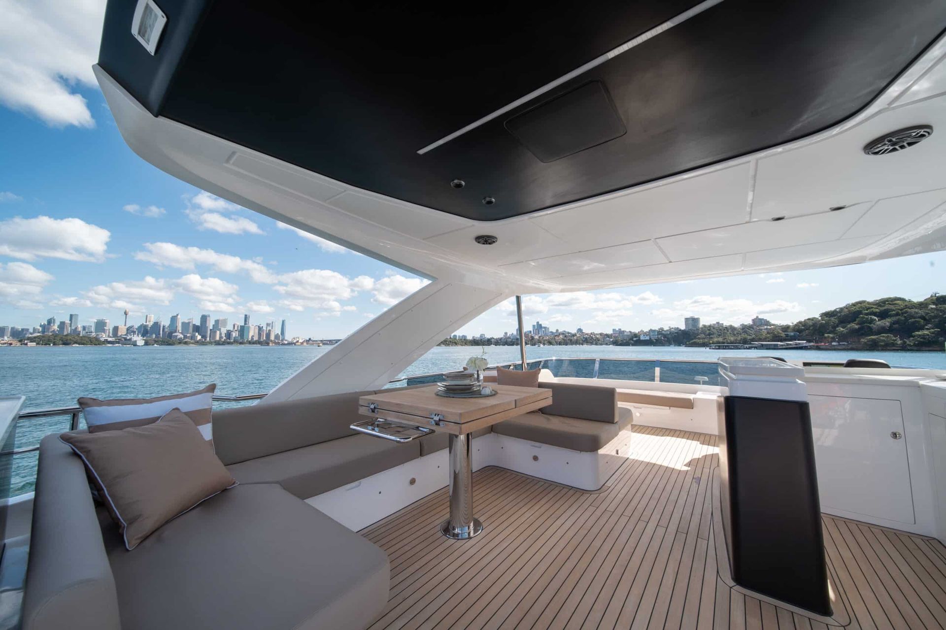 An aerial view of a yacht in the ocean with a city skyline in the background.