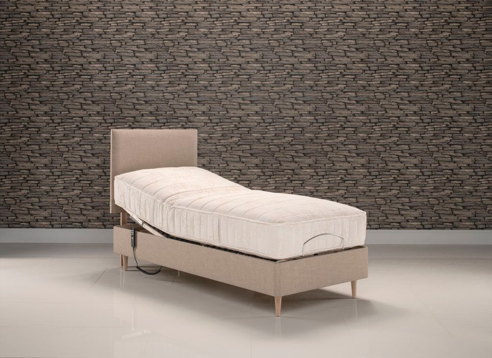 A bed with a mattress on it is sitting in front of a brick wall.