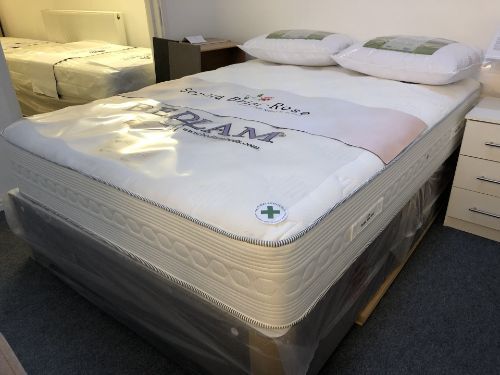 A mattress is wrapped in plastic and sitting on top of a bed.