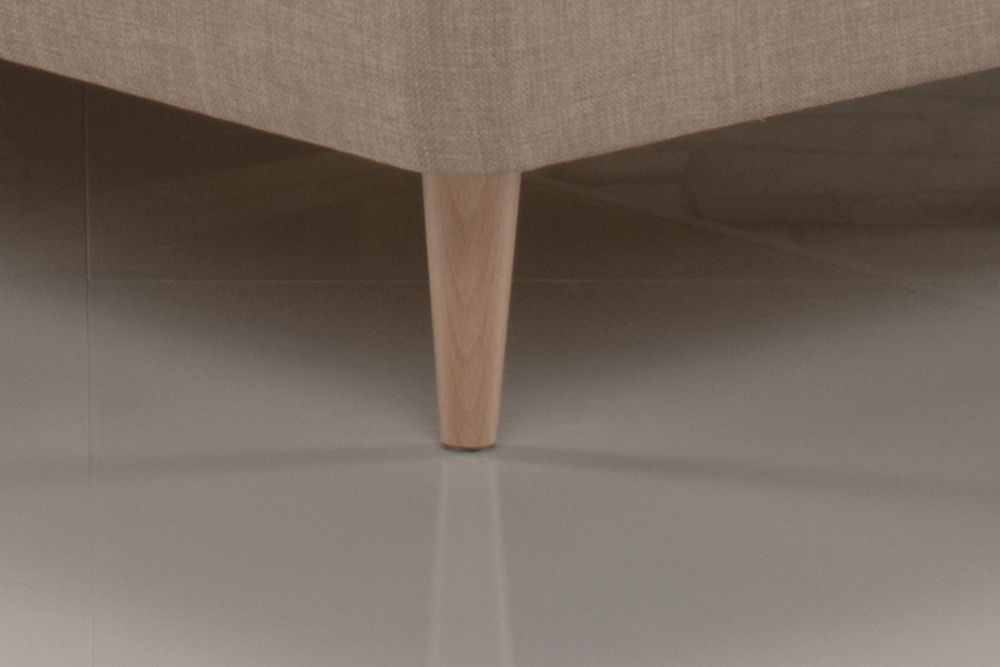 A close up of a couch with wooden legs on a tiled floor.