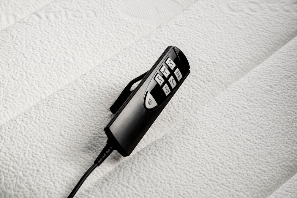 A remote control is sitting on top of a white mattress.